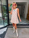 A woman wearing a sleeveless cream-colored A-line dress with a rodeo western motif pattern, styled with red sunglasses, a turquoise necklace, and bracelets. Wear to game day, rodeo or western events. SEC, game day, SMU, Texas Tech, TX Tech, OU, colts, NFL, rodeo, NFR, western