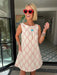 A woman wearing a sleeveless cream-colored A-line dress with a rodeo western motif pattern, styled with red sunglasses, a turquoise necklace, and bracelets. Wear to game day, rodeo or western events. SEC, game day, SMU, Texas Tech, TX Tech, OU, colts, NFL, rodeo, NFR, western
