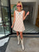 A woman wearing a sleeveless cream-colored A-line dress with a rodeo western motif pattern, styled with red sunglasses, a turquoise necklace, and bracelets. Wear to game day, rodeo or western events. SEC, game day, SMU, Texas Tech, TX Tech, OU, colts, NFL, rodeo, NFR, western