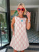 A woman wearing a sleeveless cream-colored A-line dress with a rodeo western motif pattern, styled with red sunglasses, a turquoise necklace, and bracelets. Wear to game day, rodeo or western events. SEC, game day, SMU, Texas Tech, TX Tech, OU, colts, NFL, rodeo, NFR, western