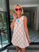A woman wearing a sleeveless cream-colored A-line dress with a rodeo western motif pattern, styled with red sunglasses, a turquoise necklace, and bracelets. Wear to game day, rodeo or western events. SEC, game day, SMU, Texas Tech, TX Tech, OU, colts, NFL, rodeo, NFR, western