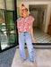A woman wearing light-wash wide-leg jeans with floral eyelet cutout on the lower legs.