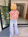 A woman viewed from behind wearing a  light-wash wide-leg jeans with eyelet cutouts.