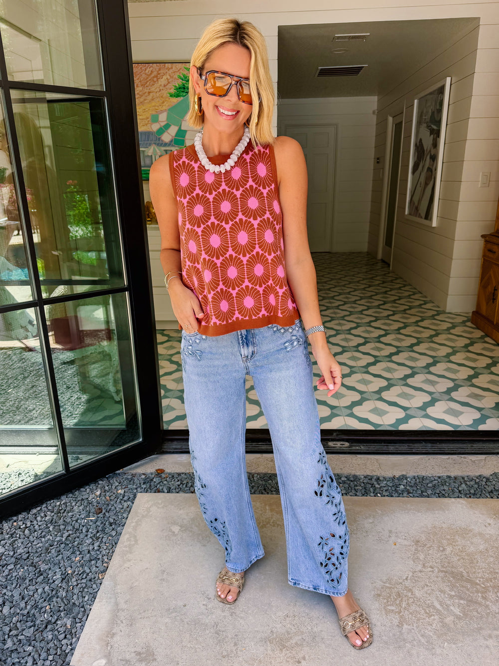 A woman wearing light-wash wide-leg jeans with floral eyelet cutout on the lower legs.