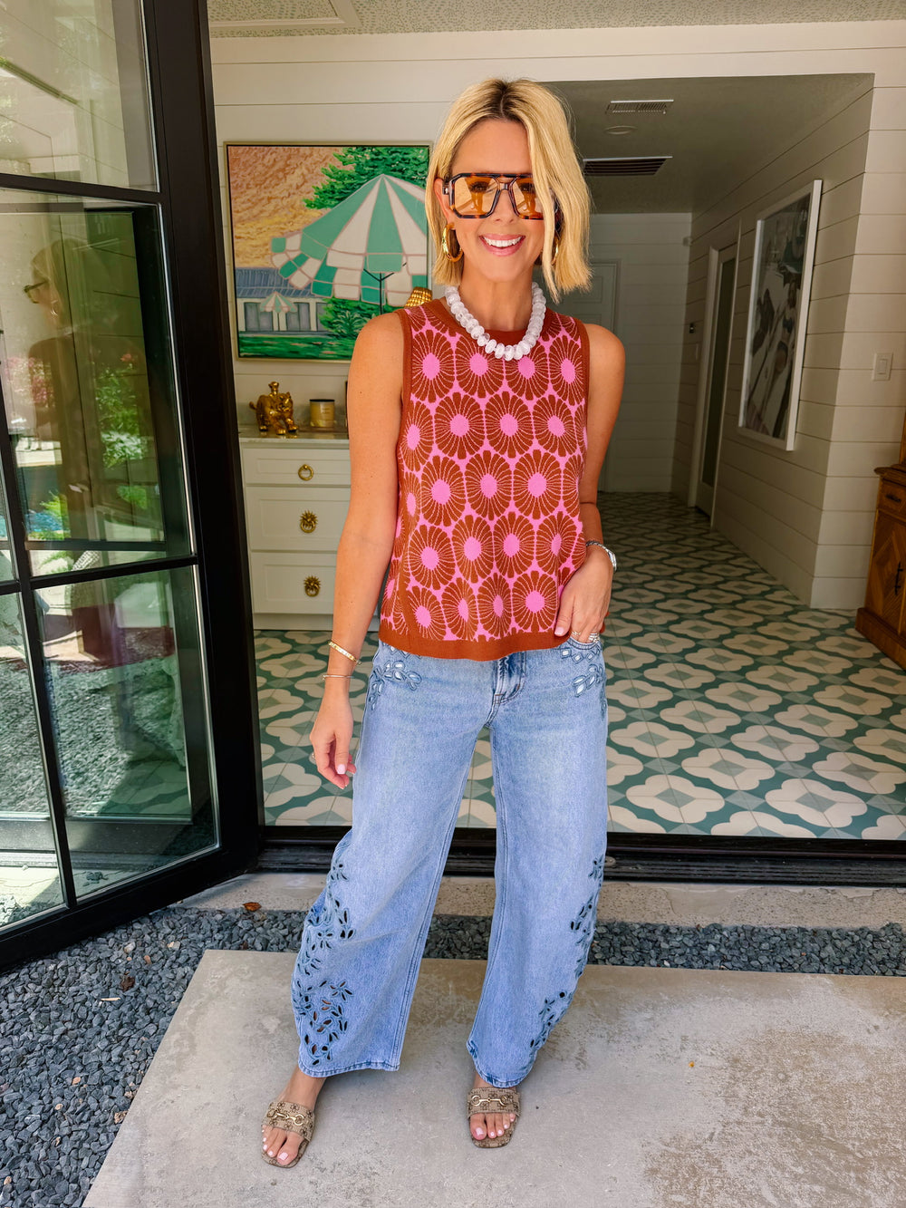 A woman wearing light-wash wide-leg jeans with floral eyelet cutout on the lower legs.