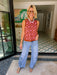 A woman wearing light-wash wide-leg jeans with floral eyelet cutout on the lower legs.