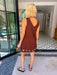 A women viewed from behind modeling a sleeveless brown dress with circular cutout grommet details along hem.