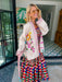 A woman wearing a cream-colored embroidered, beaded kimono-style jacket with pink striped trim and sunshine motif