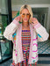 A woman wearing a cream-colored embroidered, beaded kimono-style jacket with pink striped trim and sunshine motif