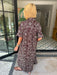 A woman wearing a brown and blue bandana patterned maxi shirt dress with short sleeves. Wear to a rodeo or western event.
