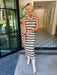 A woman wearing a sleeveless fitted dress with a multicolor geometric stripe chevron pattern and white cowboy boots. This is a fun date night dress for summer or fall.

